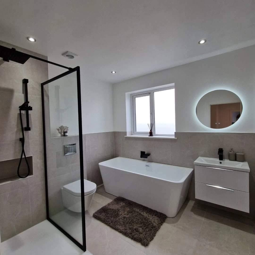 Round backlit LED mirror above a wall-hung vanity in a bathroom, Boston Spa bungalow conversion.
