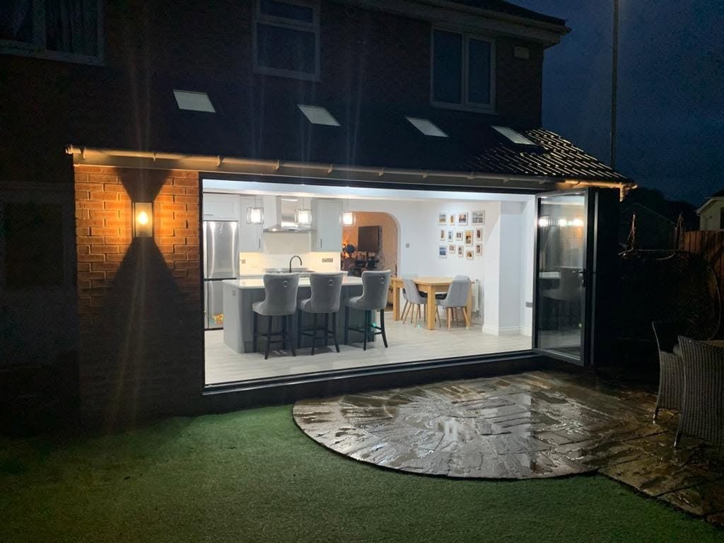 Kitchen and dining extension lit up at dusk with bifold doors open, Wakefield, electrical installation by BRO Electrical.