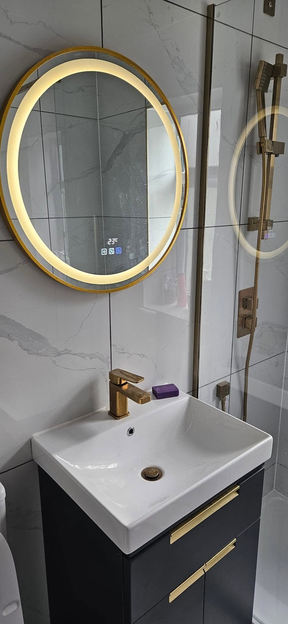 Round LED mirror and gold tap above a vanity sink in the family bathroom of a loft conversion in Leeds.