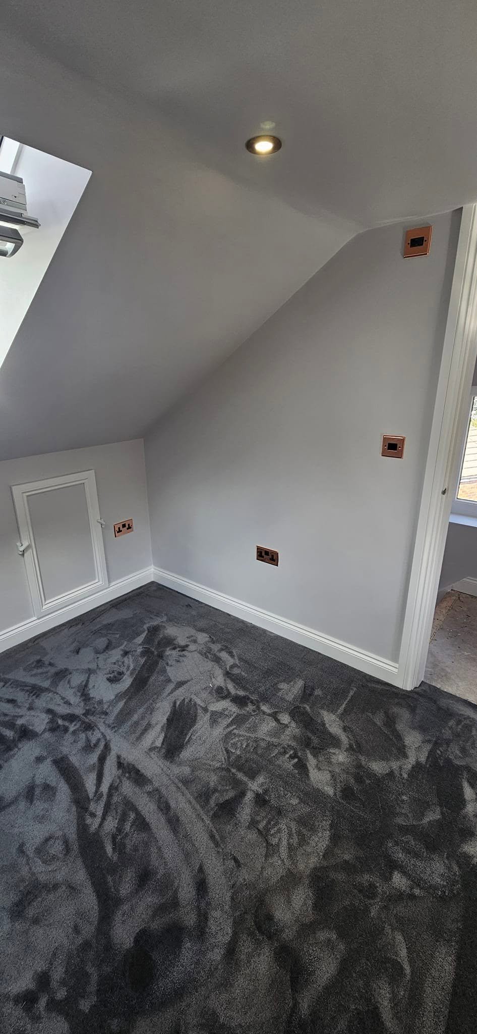 Copper-finish sockets and a ceiling spotlight in a loft conversion bedroom, Leeds.