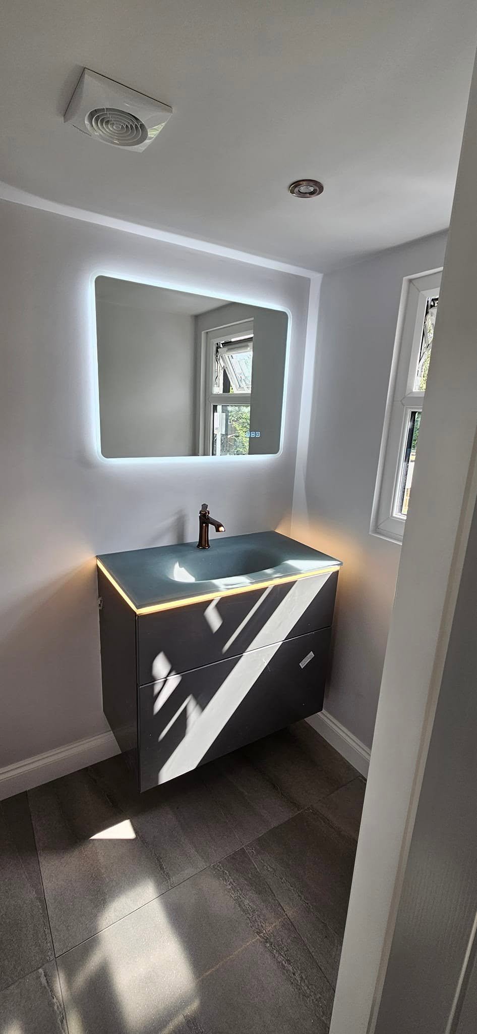 En-suite vanity with backlit mirror and downlight, loft conversion in Leeds.