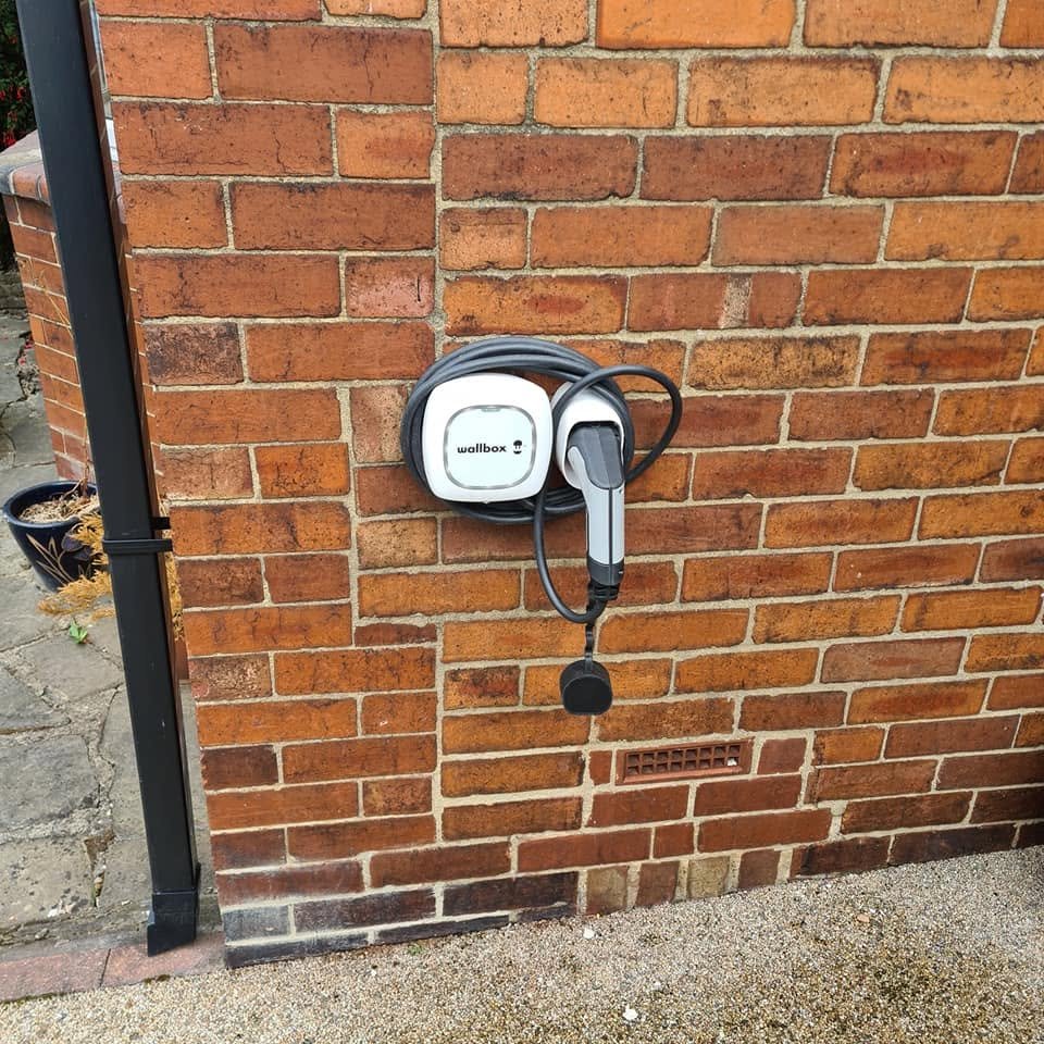 Genuine BRO Electrical EV charger installation on an exterior brick wall, with cable neatly coiled and a cable holster fitted below