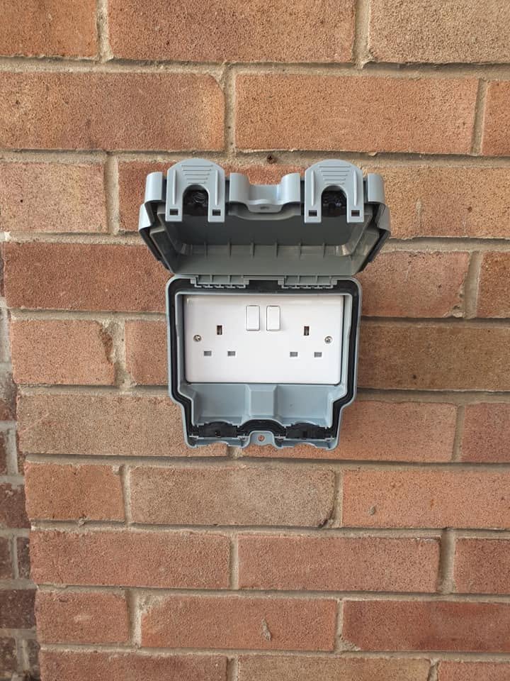 Weatherproof outdoor double socket fitted to an exterior brick wall, Leeds