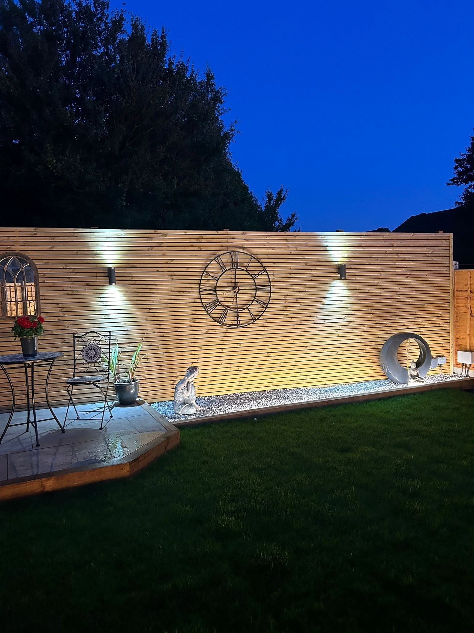 Landscaped garden at night with an illuminated timber feature wall, architectural up/down lighting and lit water feature, Leeds