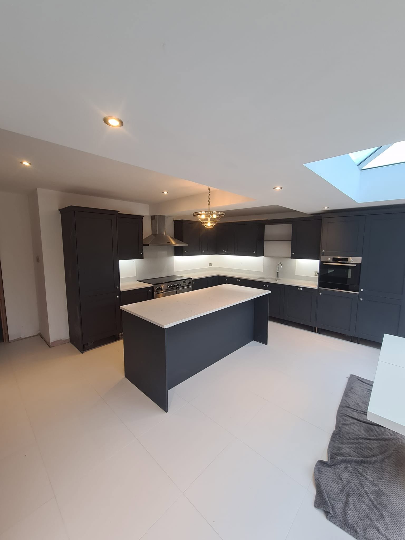 Substantial dark fitted kitchen with island, rooflight, feature pendant and layered downlighting, Leeds