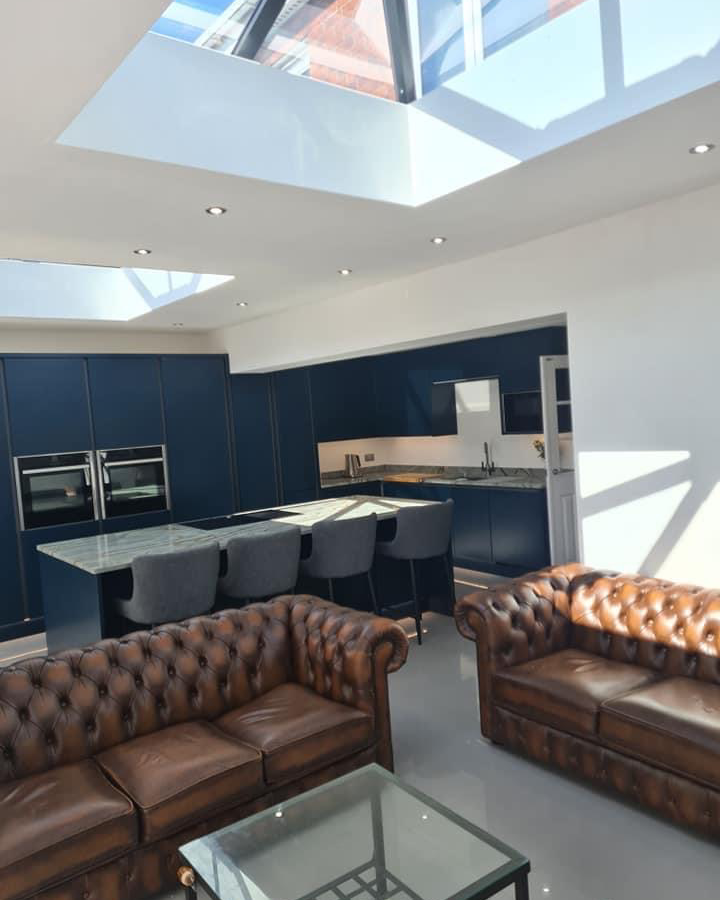 Open-plan kitchen and living extension with dark blue cabinetry, rooflights and leather sofas, Leeds