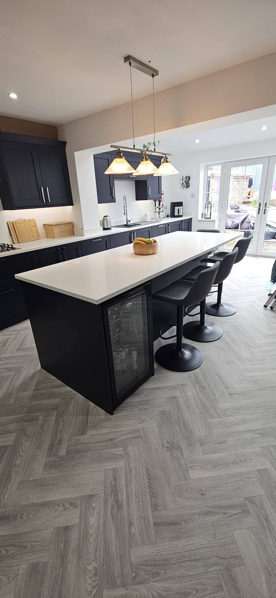 Kitchen island with three pendant lights above, dark cabinetry, Leeds
