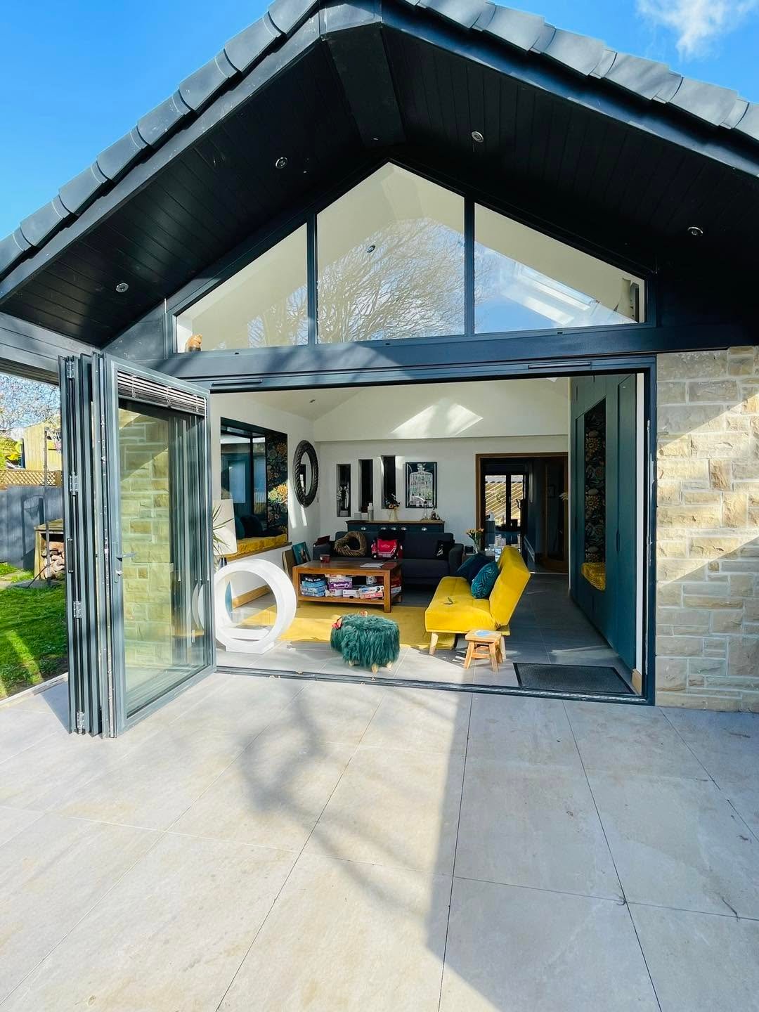Modern stone extension with large triangular glazing and open bifold doors, Leeds